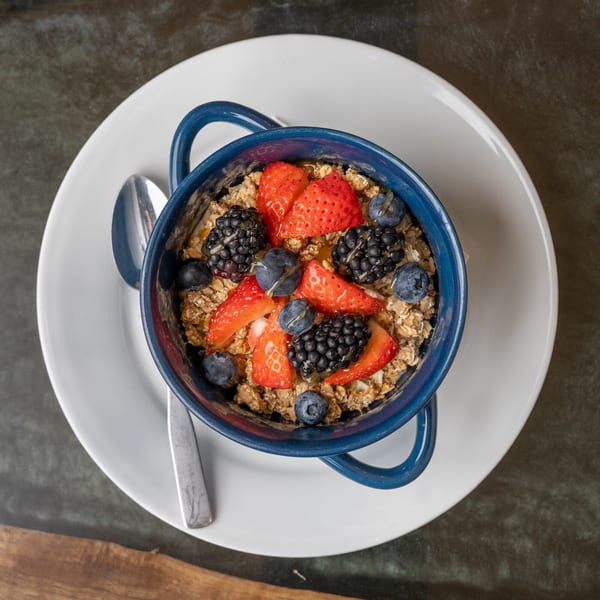 Overhead view of a blue bowl of oatmeal topped with fresh strawberries, blueberries, and blackberries.