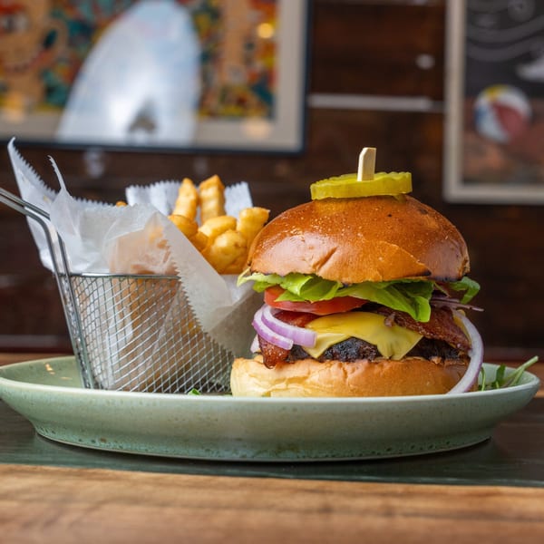 A juicy burger with cheese, bacon, lettuce, tomato, and onion, served with a side of fries.