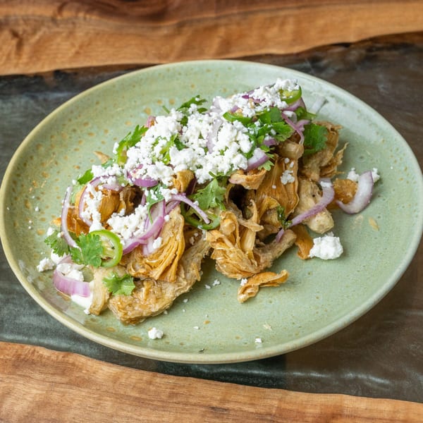 Crispy fried chicken skin chicharrones topped with crumbled cheese, red onions, cilantro, and jalapeños.