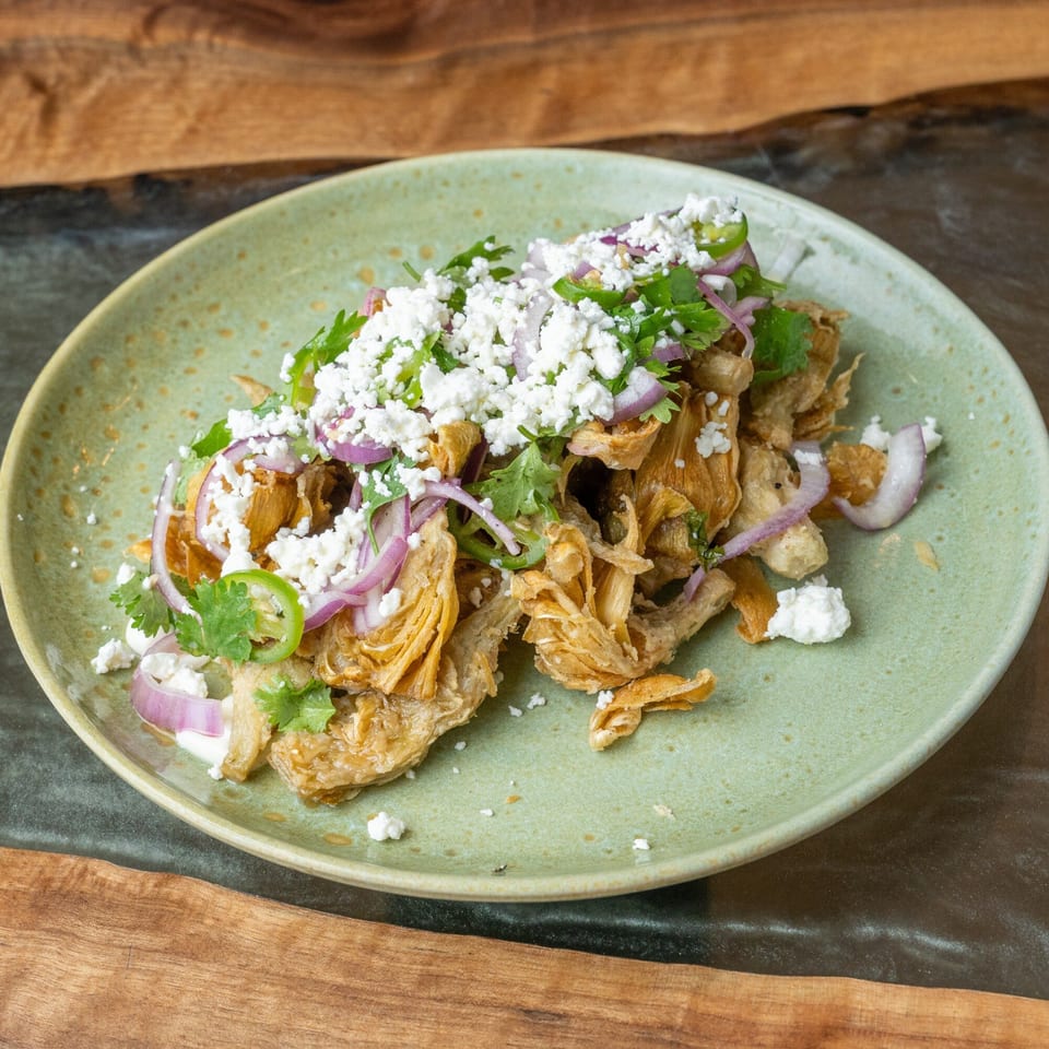 Crispy fried chicken skin chicharrones topped with crumbled cheese, red onions, cilantro, and jalapeños.
